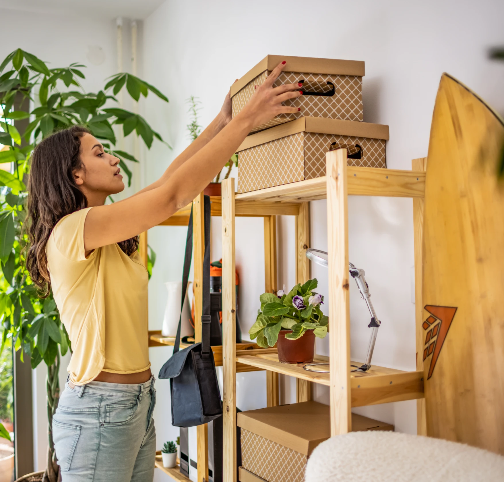 Woman organizing boxes on wooden shelf.