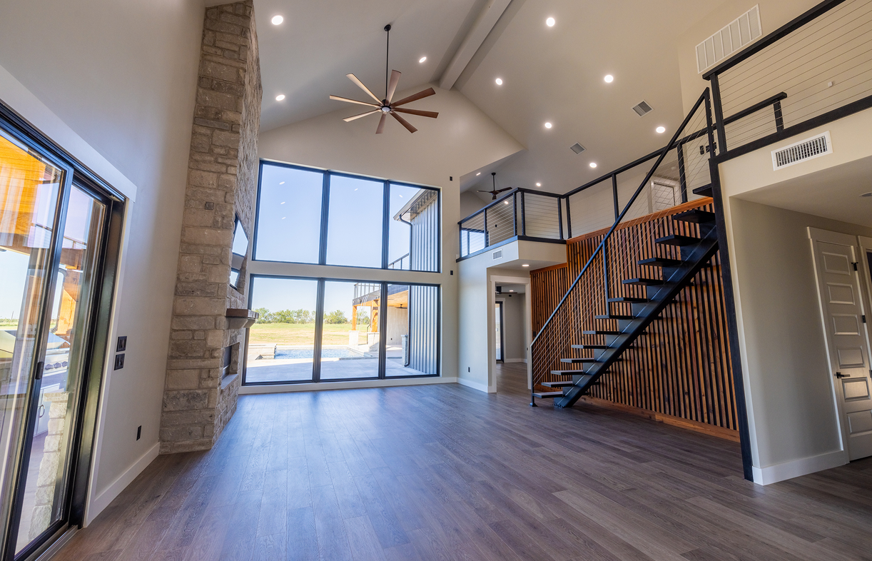 Modern living room with large windows and staircase.